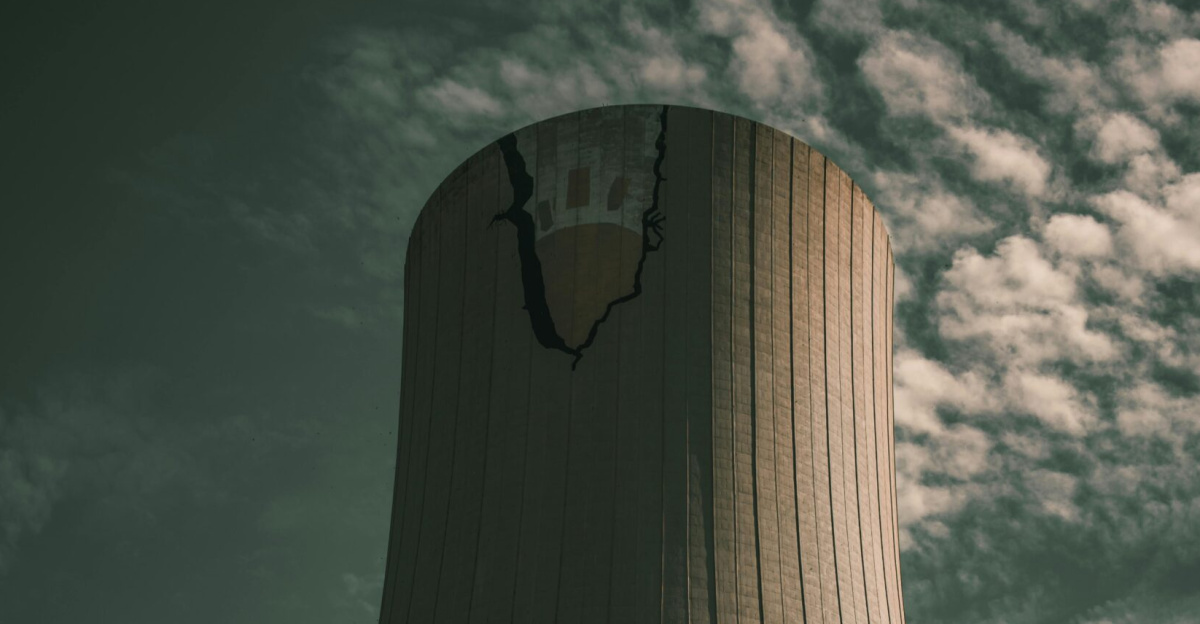 A towering industrial cooling tower captured from below against a partly cloudy sky.