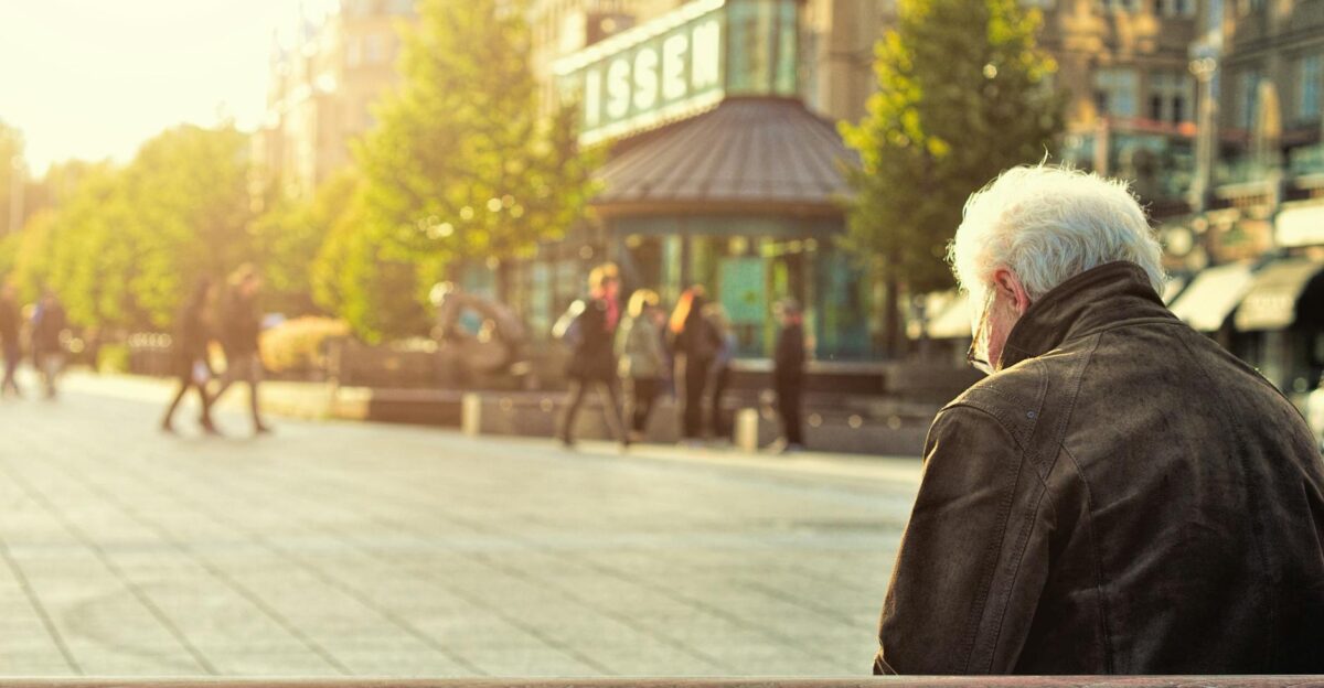 A senior man sitting on a bench in Jyv skyl Finland Captured during a sunny day in the city square