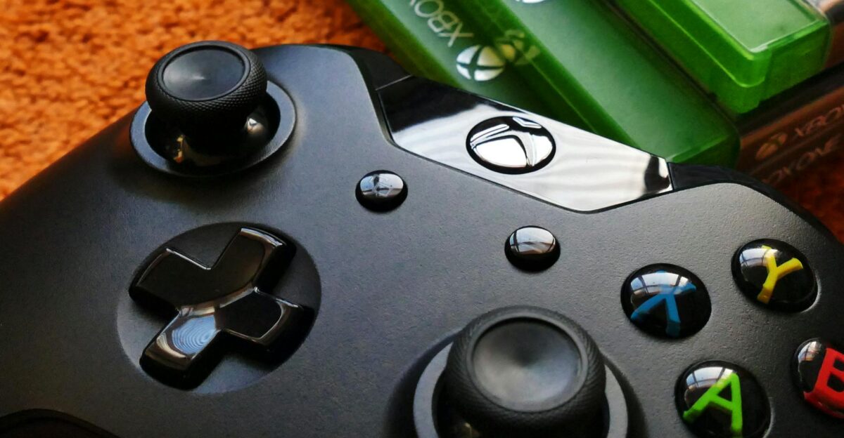 Xbox controller close-up with game cases on orange background