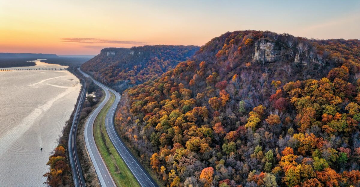 A stunning aerial view of a highway alongside a river with vibrant fall foliage in Minneiska MN
