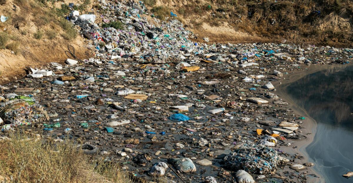 Plastic waste and debris polluting a riverbank highlighting environmental challenges