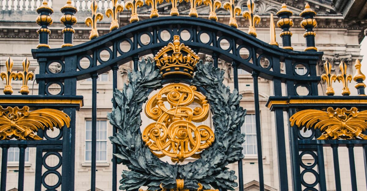 Detailed view of the ornate gold and black iron gate at Buckingham Palace London