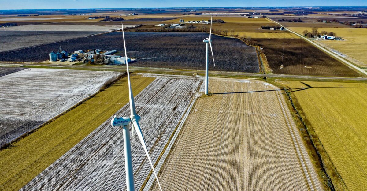 Aerial shot of wind turbines over snow-dusted farmland promoting renewable energy