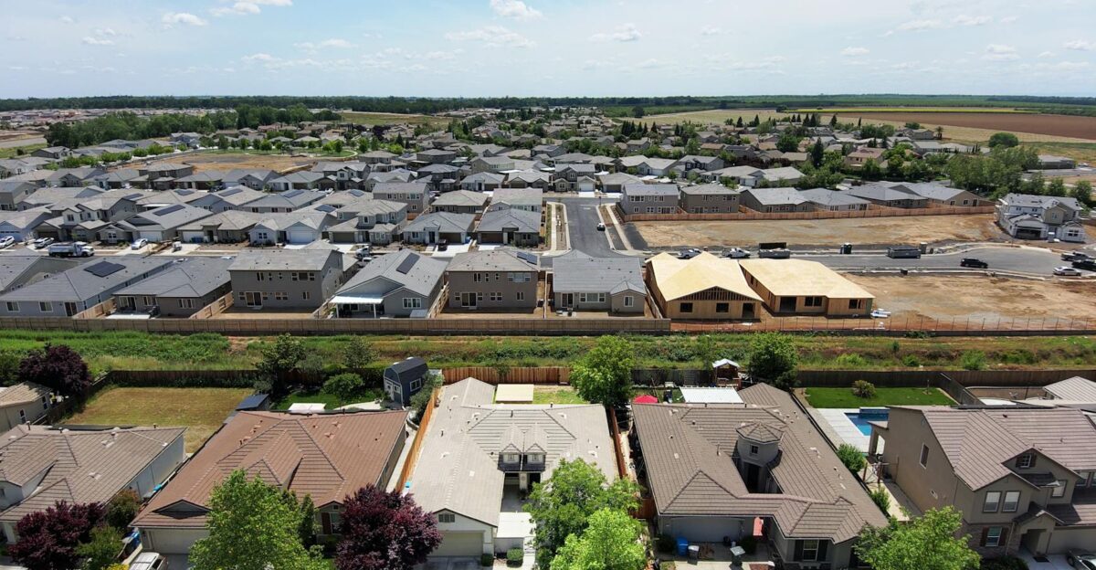Drone view of suburban neighborhood with new housing developments and green surroundings