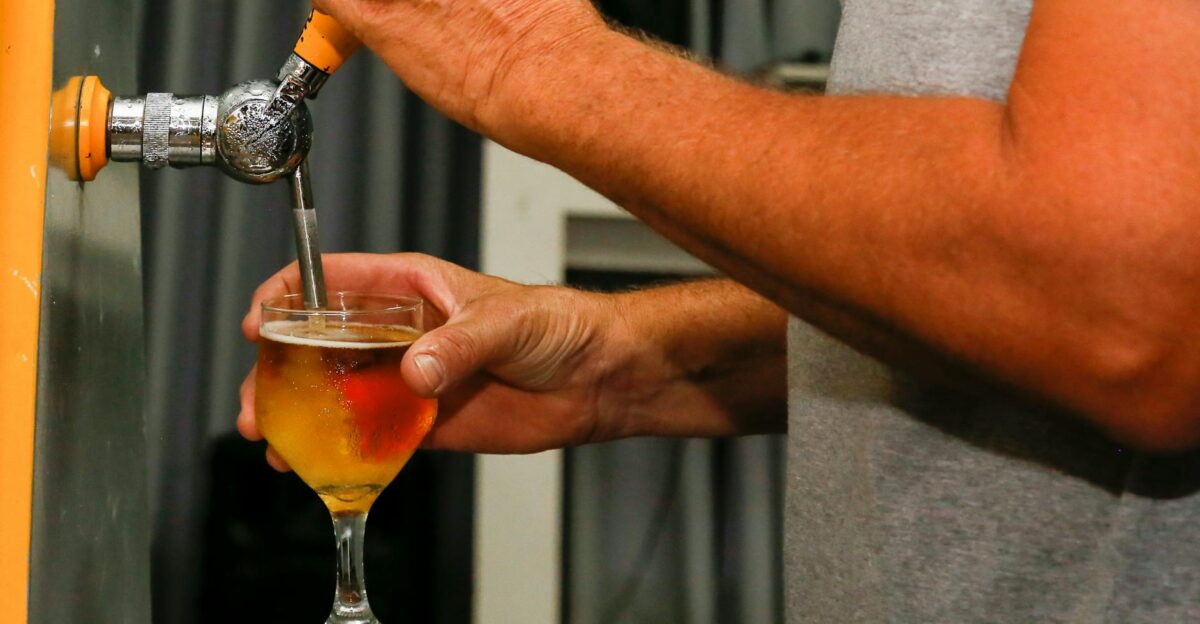 Close-up of a man s hands pouring a draft beer into a glass from a tap
