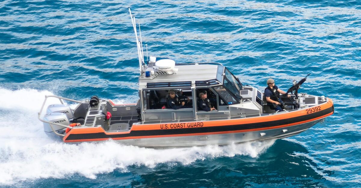 Dynamic U S Coast Guard patrol boat speeding through blue ocean waters showcasing security and marine operations