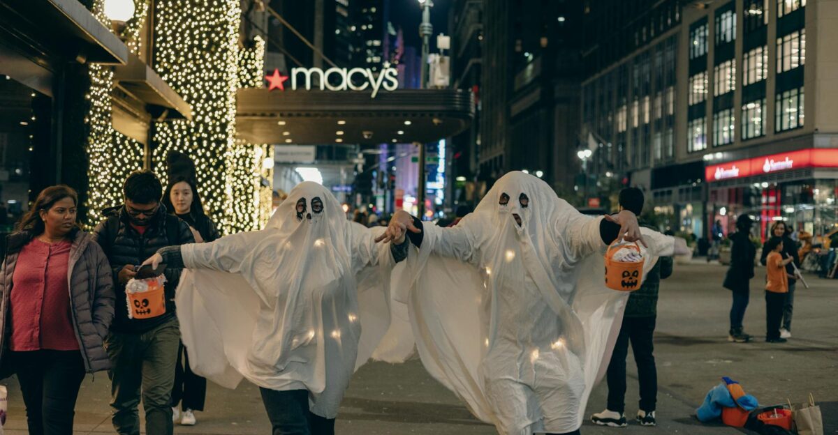 Adults in ghost costumes walk in New York City at night celebrating Halloween