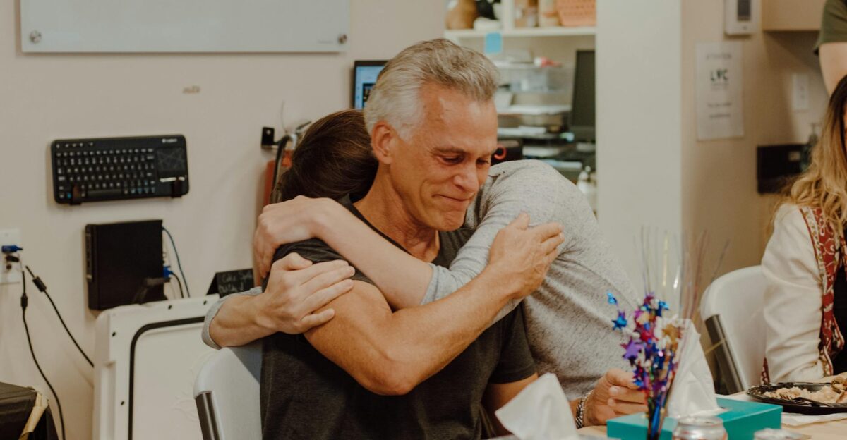 Emotional embrace among colleagues during a heartfelt gathering in an office setting