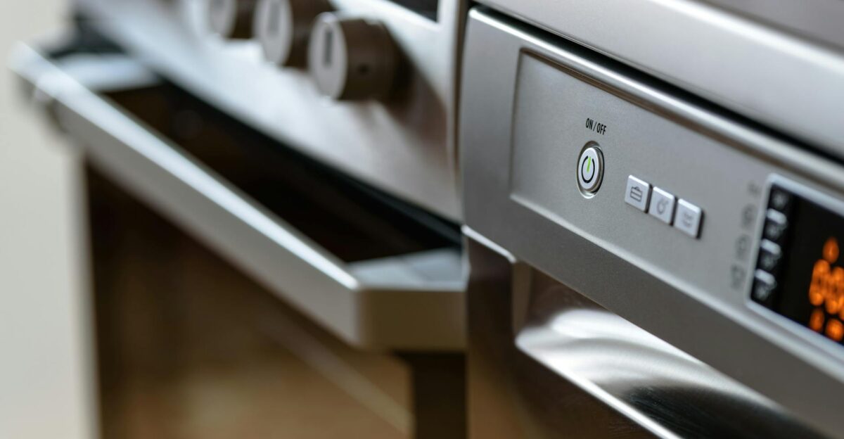 Close-up view of modern stainless steel kitchen appliances with focus on dishwasher and oven