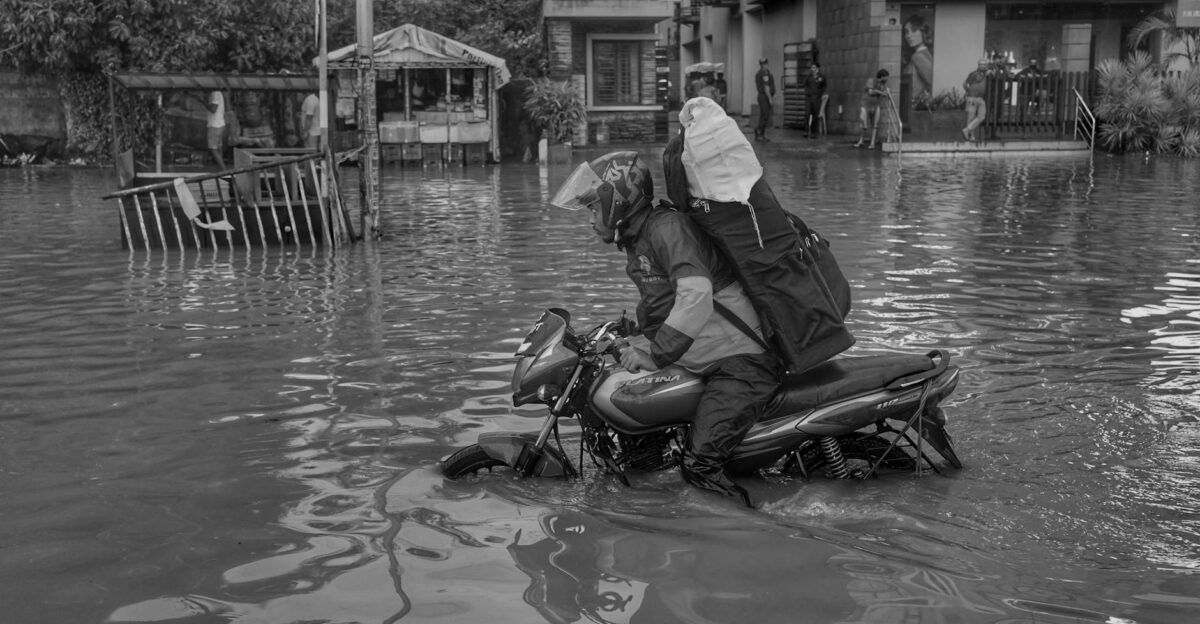 A motorcyclist in gear tackles urban flooding in Kolkata India highlighting a natural disaster