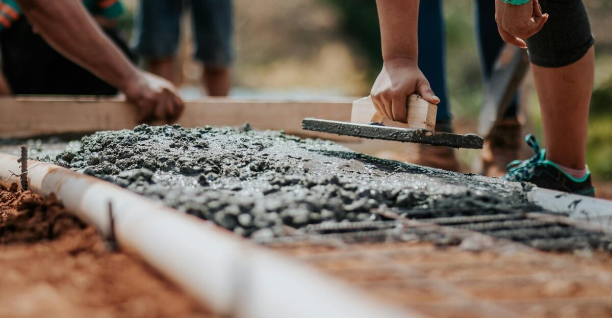 Construction workers leveling fresh cement on a sunny day at an outdoor site