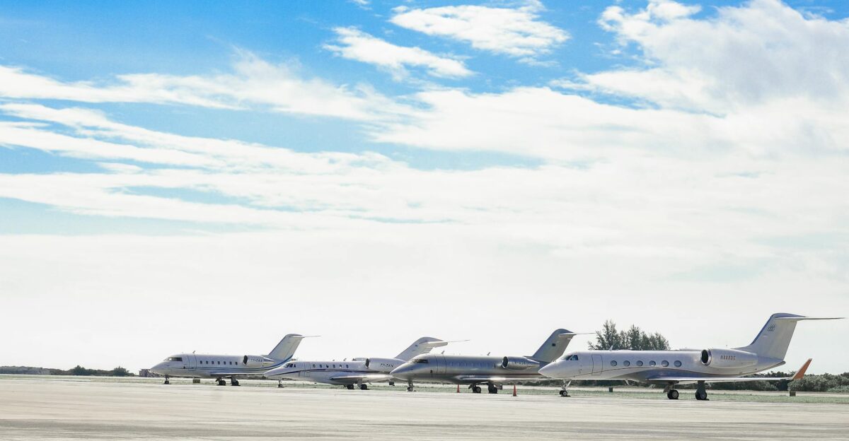 Row of private jets parked on a clear day at an open runway showcasing aviation and luxury travel