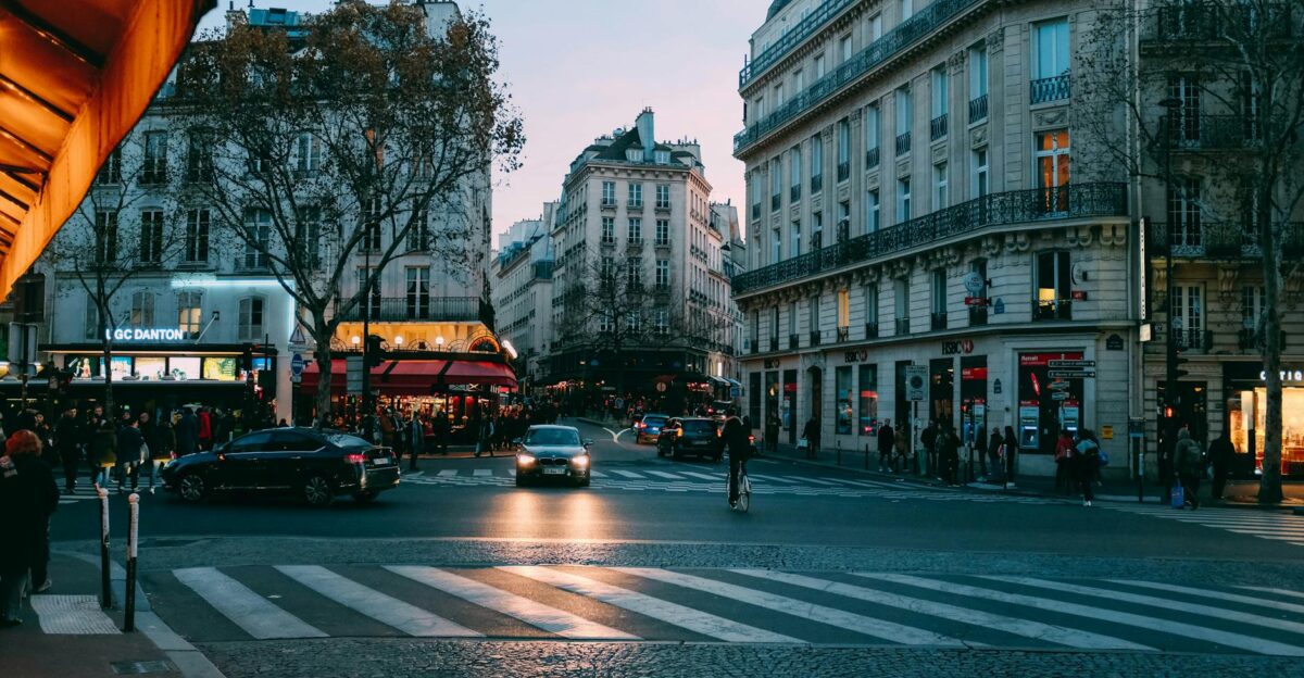 Urban street scene at dusk with cars and pedestrians in a bustling city intersection