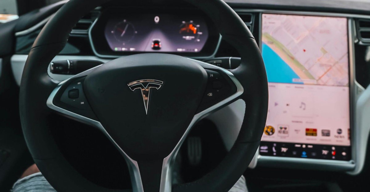 Interior view of a Tesla Model X steering through palm-lined streets of Santa Monica at twilight.