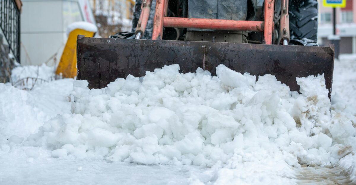 Snow plow clearing icy street after heavy winter snowstorm Extreme cold weather conditions
