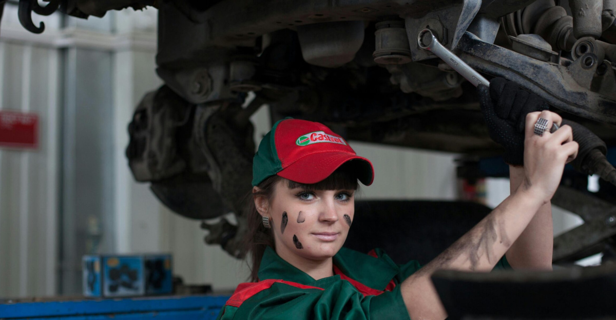 Female mechanic maintaining a car in an auto repair shop, showcasing skill and concentration.
