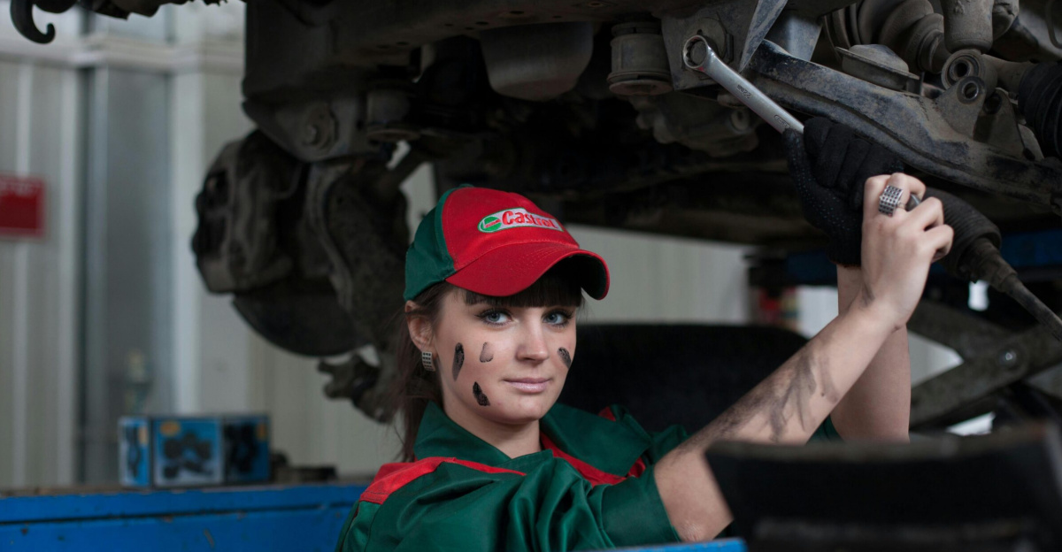 Female mechanic maintaining a car in an auto repair shop, showcasing skill and concentration.