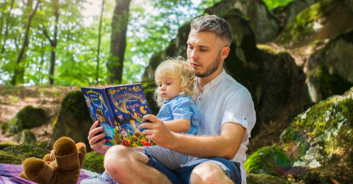 Father and toddler bonding over a book in a sunny forest setting