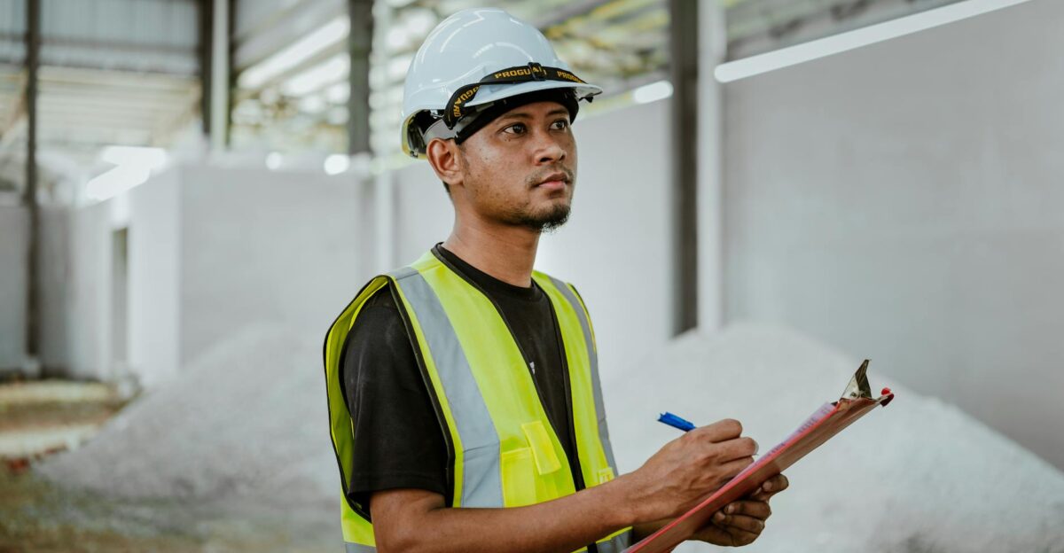 Asian construction worker in a factory setting using a clipboard for inspection tasks in Banting Malaysia