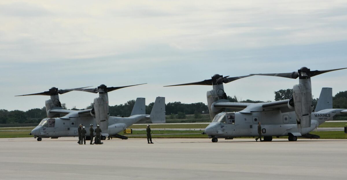 Two military aircraft parked at an airbase with personnel nearby showcasing aviation technology