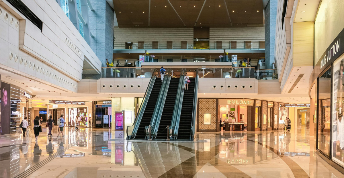 Modern shopping mall interior with escalators and luxury stores in Hong Kong.