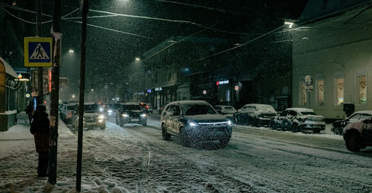Urban street scene at night with snow cars and streetlights illuminating the roadway