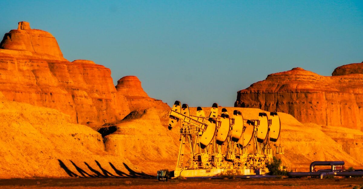 Line of pumpjacks against a stunning rocky landscape at sunset in Karamay Xinjiang China