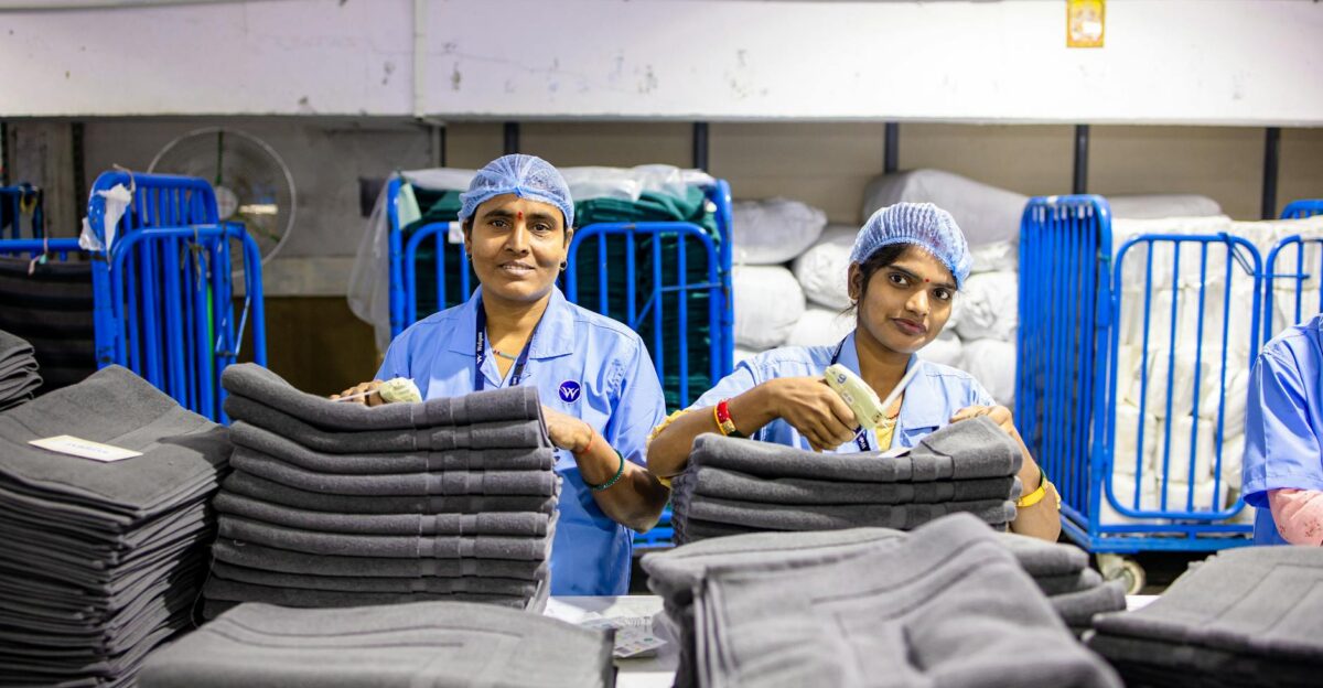 Two textile workers sorting linens in a factory setting