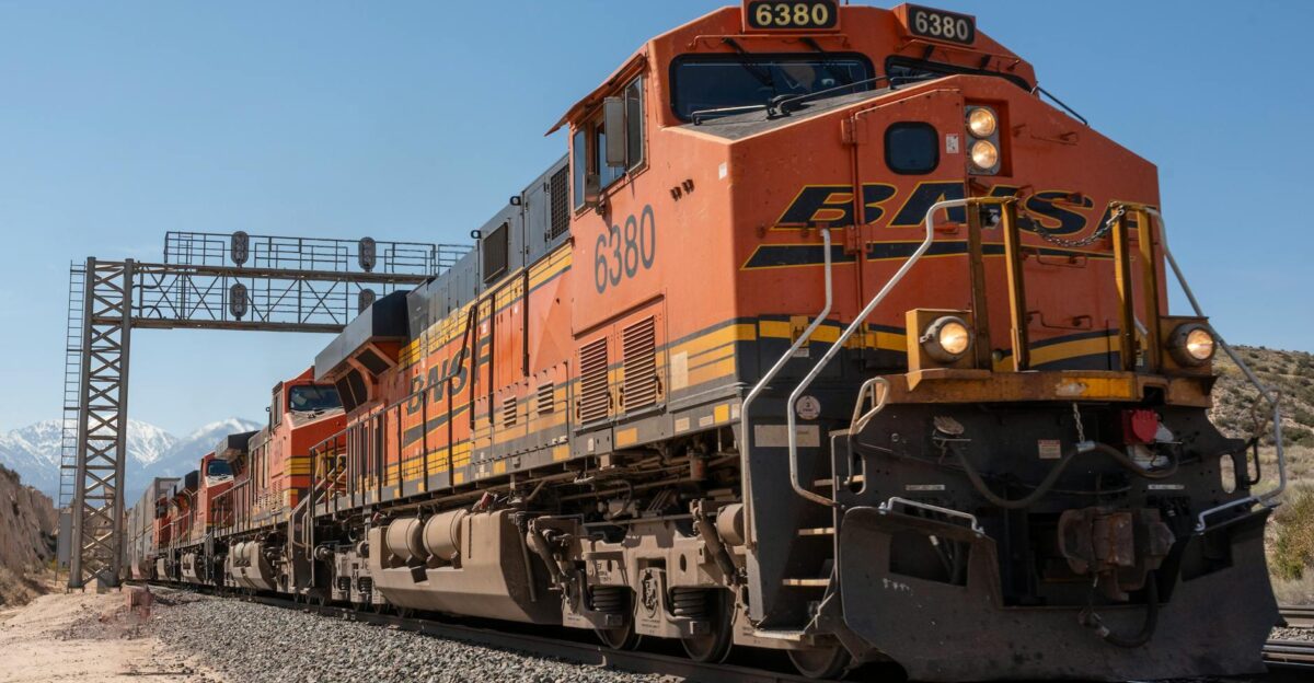 A powerful freight train traveling on tracks with scenic California mountains in the background