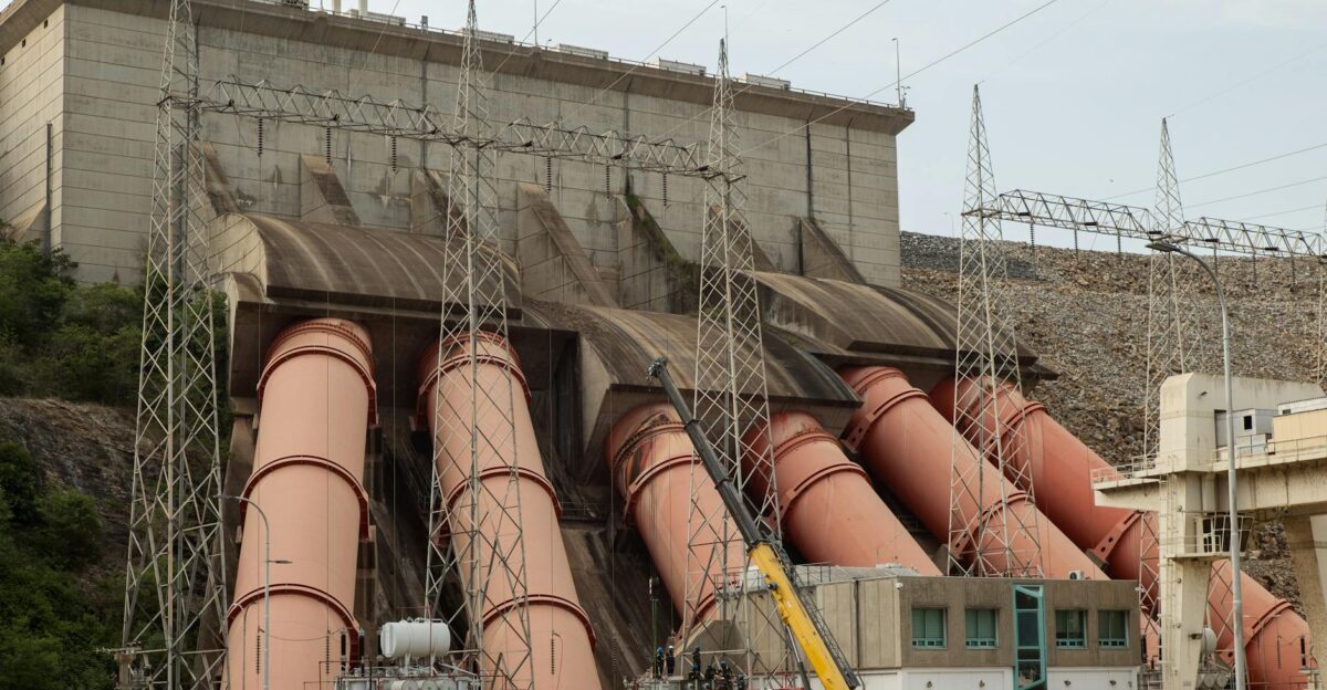 Industrial view of a massive hydroelectric dam with large pipes and power lines