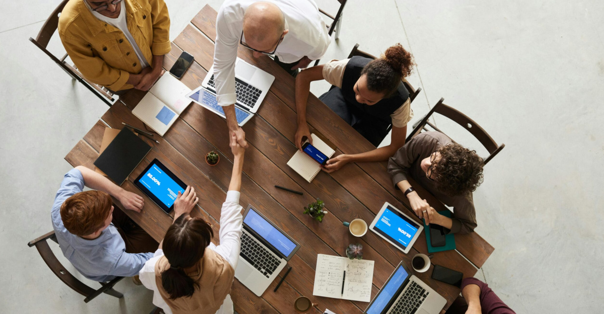 Top view of a diverse team collaborating in an office setting with laptops and tablets, promoting cooperation.