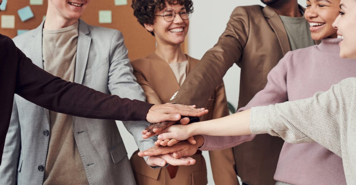 A group of happy diverse colleagues celebrating teamwork and cooperation with a group high five indoors