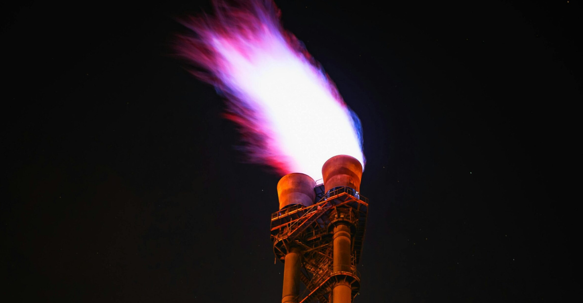 Dramatic night photo of gas flare on industrial facility emitting a powerful flame.