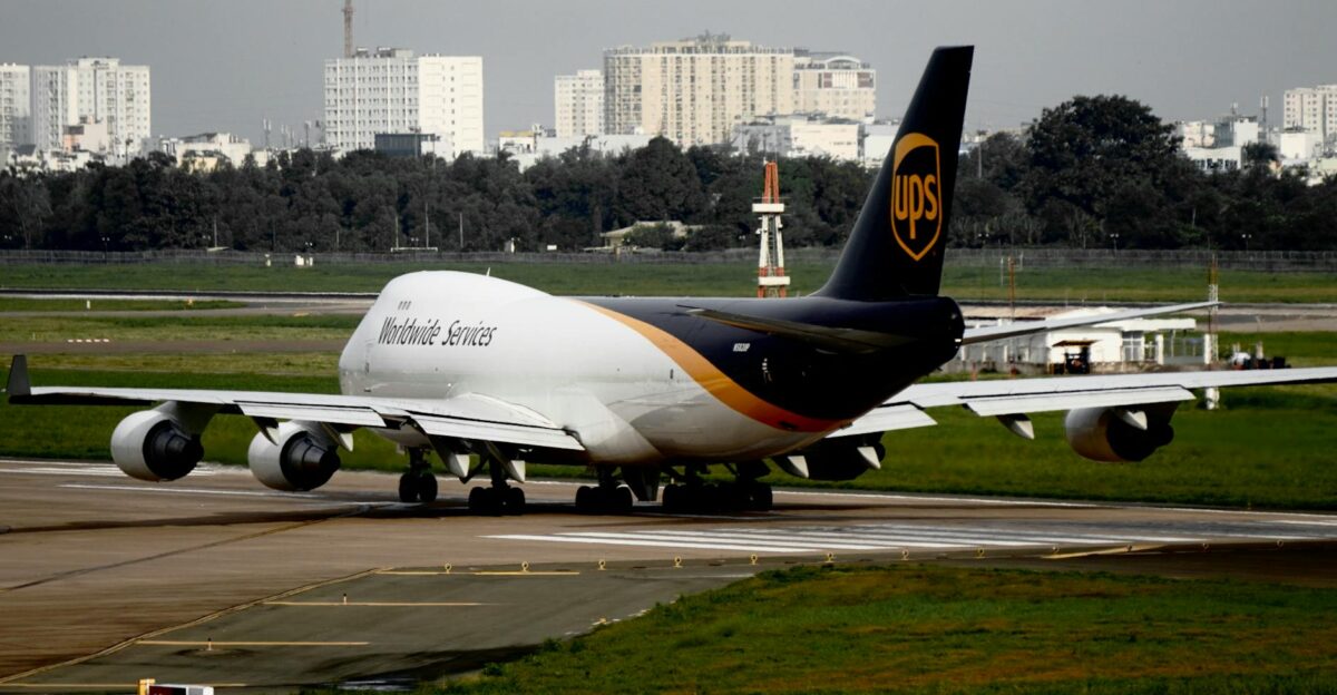 UPS cargo aircraft taxiing on runway at an airport with cityscape background