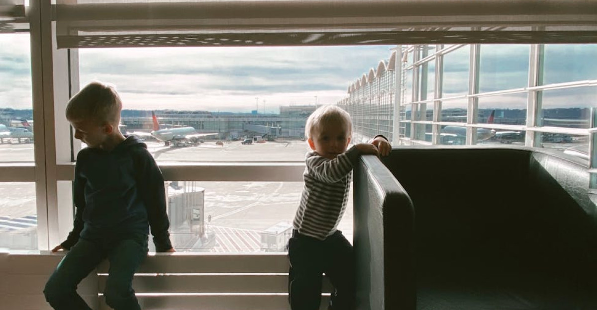 Two children play in an airport lobby with modern architecture and glass surroundings
