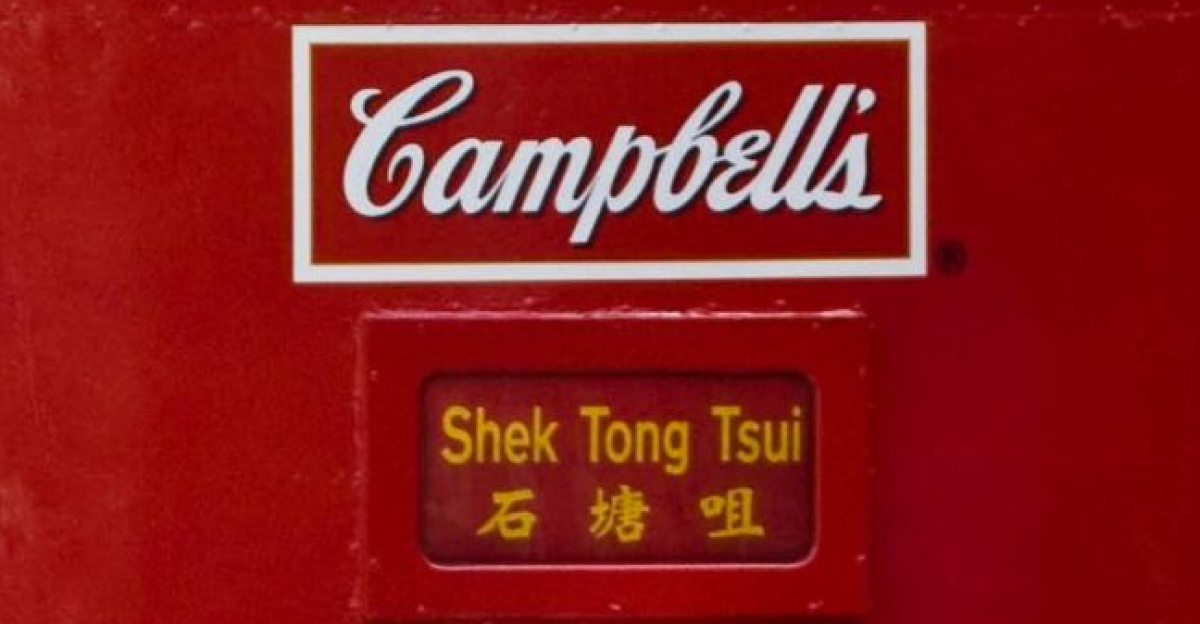 A decorated tram with Campbell's soup theme traveling through the vibrant streets of Hong Kong Island.