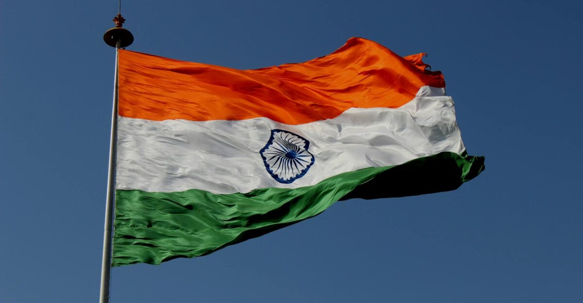The Indian national flag waves proudly against a clear blue sky symbolizing unity and pride
