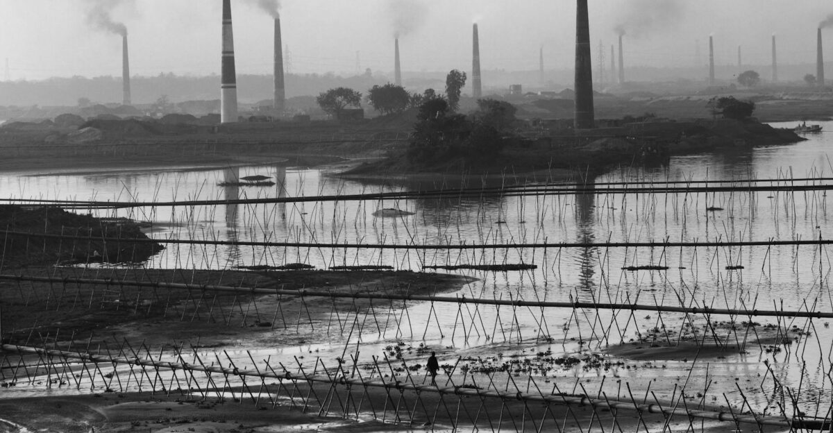 Black and white view of industrial smokestacks in Keraniganj Bangladesh reflecting in the river
