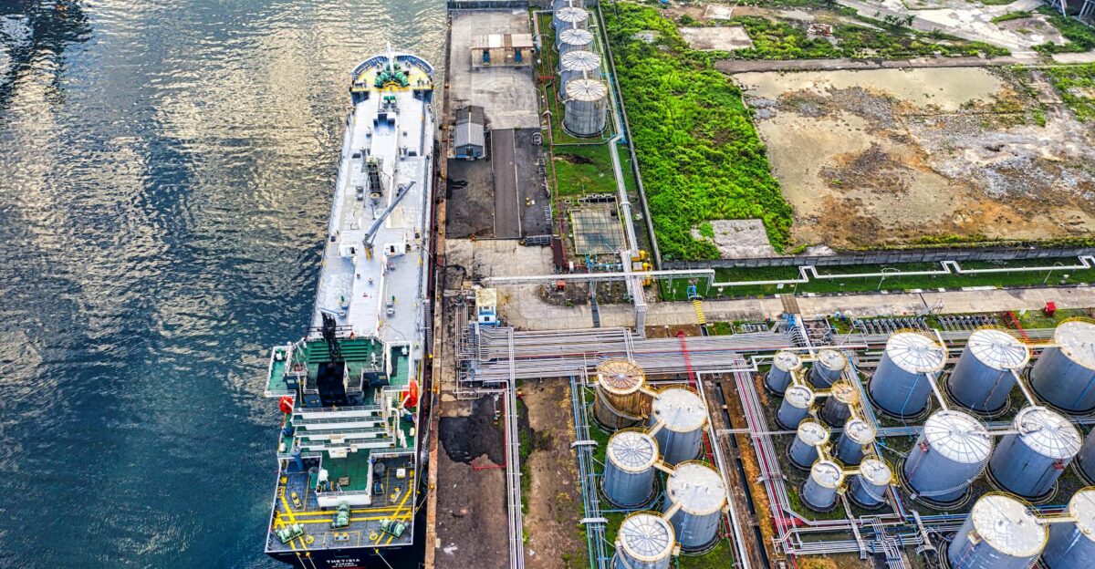 Aerial view of a ship docking at an industrial port with storage tanks in North Jakarta