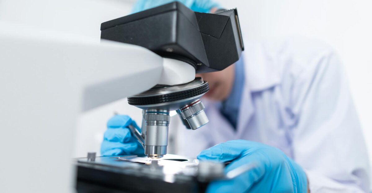 Close-up of a scientist examining samples under a microscope in a lab setting