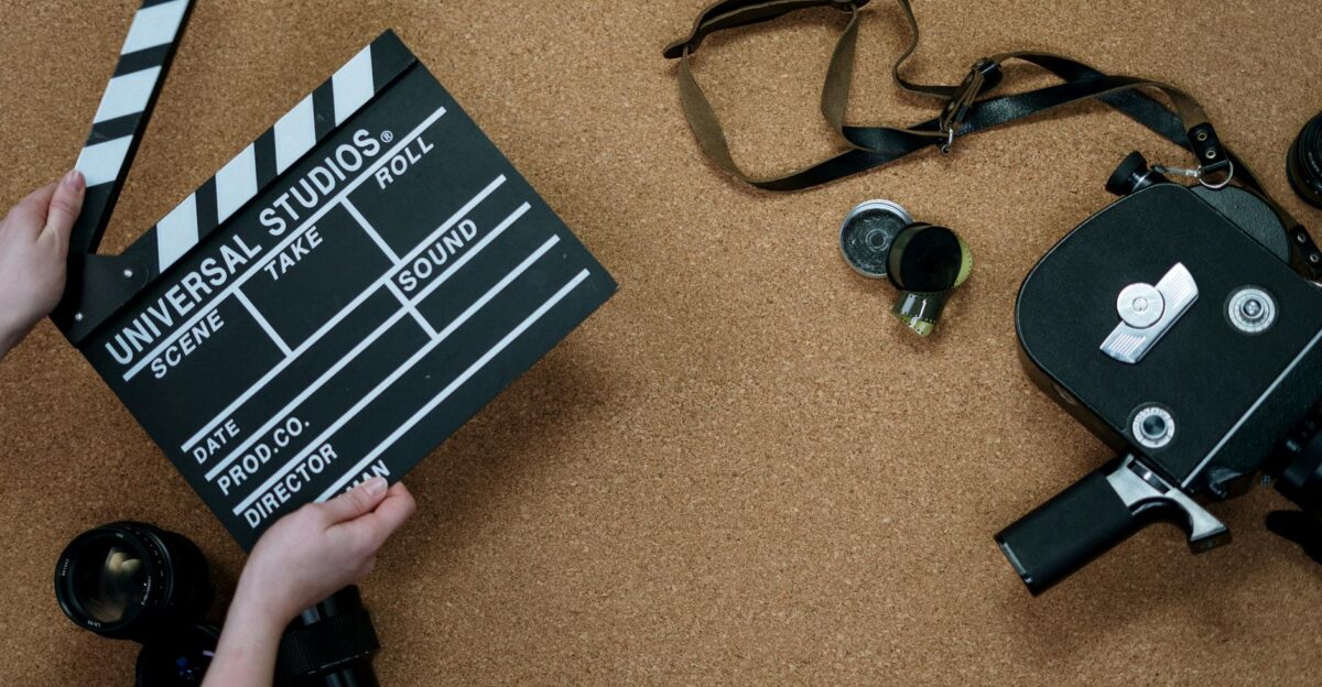 Top view of vintage film camera and clapperboard on cork background evoking old cinema vibes