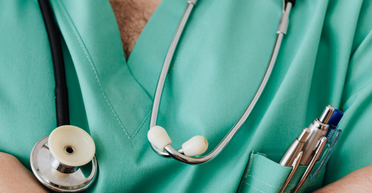 Close-up of a healthcare professional with arms crossed wearing medical scrubs and stethoscope.