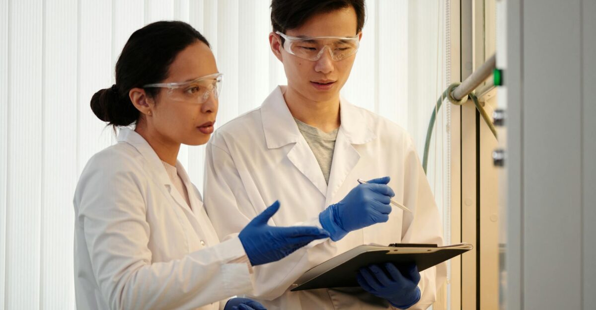 Researchers discussing data in a laboratory setting wearing safety gear and blue gloves