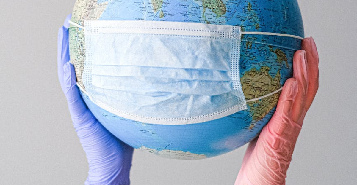 Hands in gloves holding a globe with a mask symbolizing global health and pandemic protection