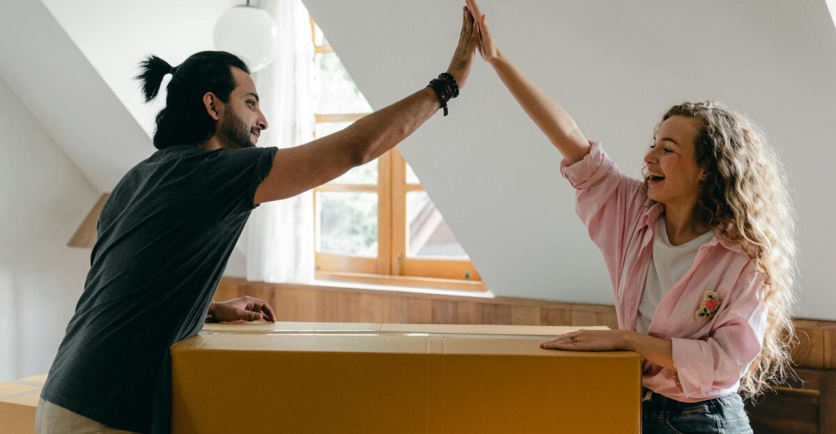 Young couple high-fiving in their new home happily surrounded by moving boxes
