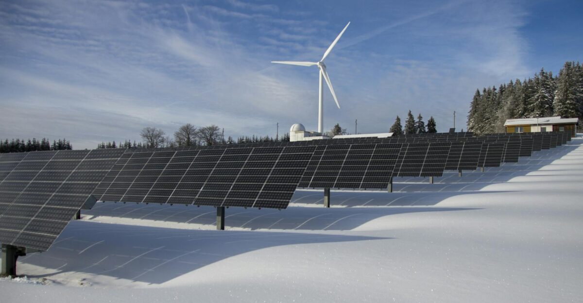 Solar panels and wind turbine in a snowy landscape showcasing renewable energy sources