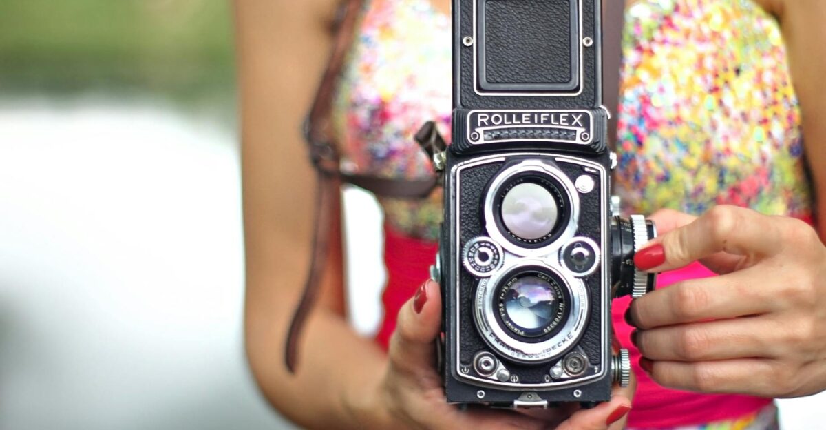 Close-up of a vintage Rolleiflex camera held by a woman in a colorful outfit