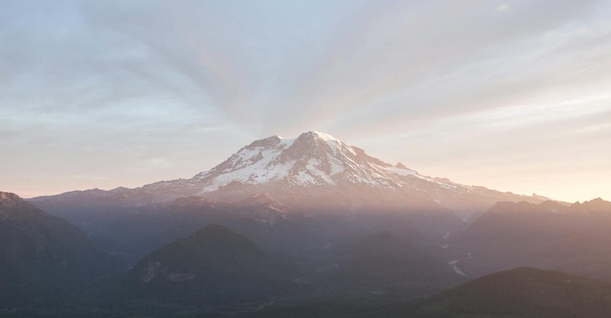 A breathtaking sunrise over Mount Rainier with snow-capped peaks and atmospheric mist