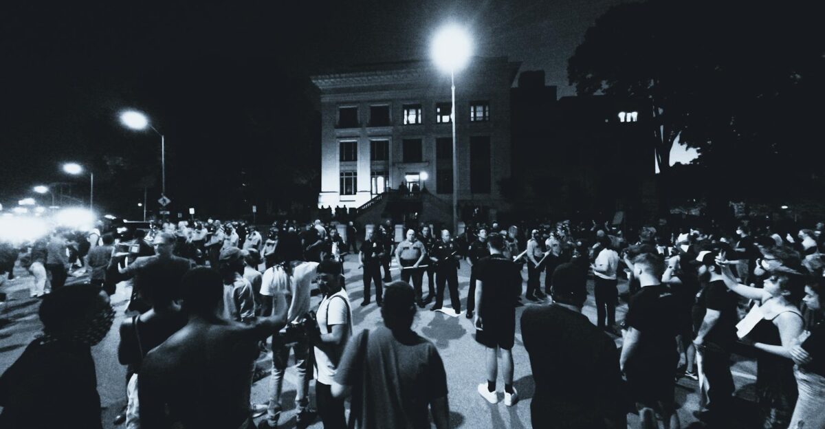A monochrome scene of a large crowd gathering for a nighttime protest in Chattanooga TN