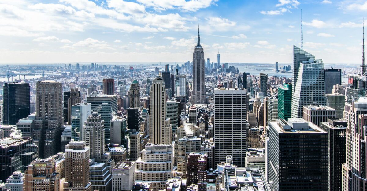 A stunning aerial view of New York City s skyline featuring the iconic Empire State Building under a bright blue sky